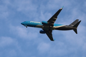 Frachtflugzeug vor blauem Himmel und Wolken von unten.