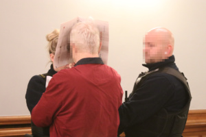 Angeklagter im Gerichtssaal mit Wachtmeistern.