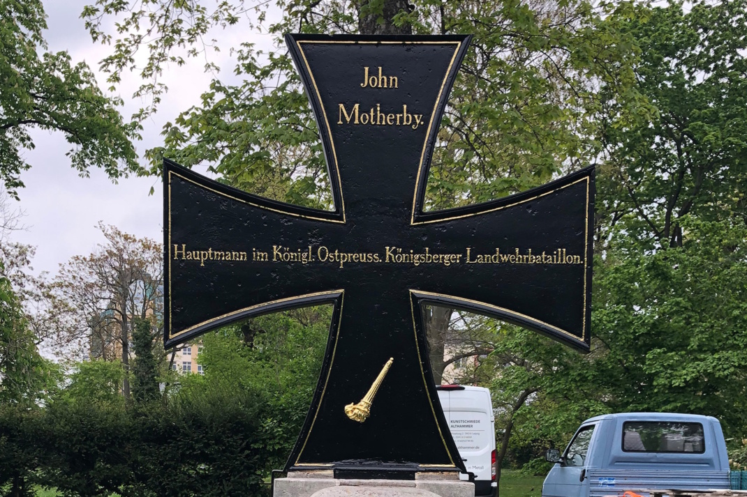 Gleichmäßiges Grabkreuz mit Inschrift.