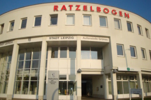 Äußere Aufnahme des Ratzelbogens mit seiner hellen Fassade und rotem Schriftzug.