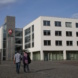 Arbeitsagentur Leipzig, Außenaufnahme. Zwei Personen spazieren über den Vorplatz.